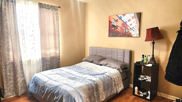 bedroom with multiple windows and dark wood-type flooring