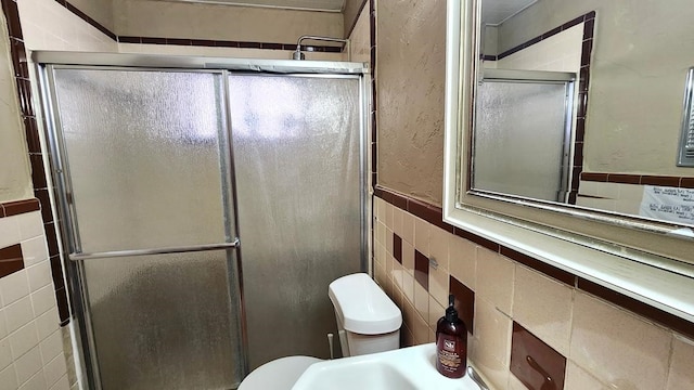 bathroom with tile walls, an enclosed shower, and toilet