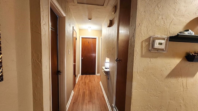 hallway with a textured ceiling and hardwood / wood-style floors