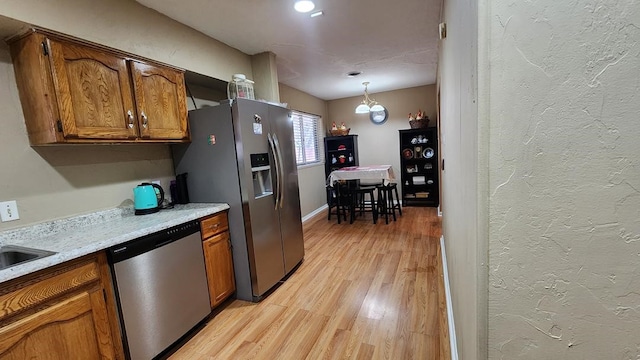 kitchen featuring light wood-type flooring, pendant lighting, and stainless steel appliances