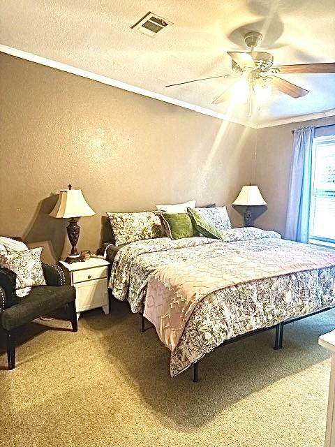 carpeted bedroom featuring crown molding, a textured ceiling, and ceiling fan