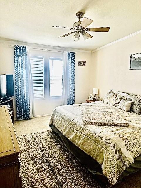 carpeted bedroom featuring a textured ceiling, ornamental molding, and ceiling fan