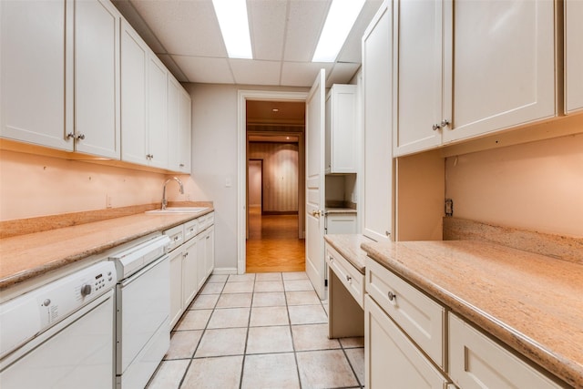 kitchen with sink, light tile patterned flooring, white cabinetry, and white dishwasher