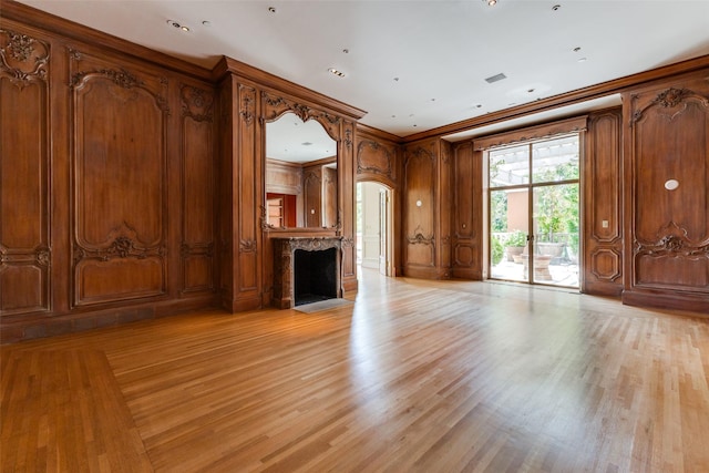 unfurnished living room featuring light wood-type flooring and ornamental molding