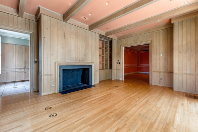 unfurnished living room with light hardwood / wood-style flooring, beam ceiling, and wooden walls