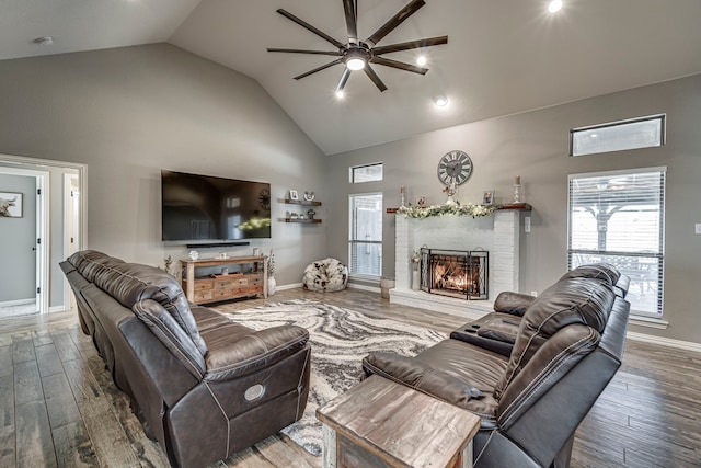 living room with hardwood / wood-style flooring, ceiling fan, vaulted ceiling, and a fireplace