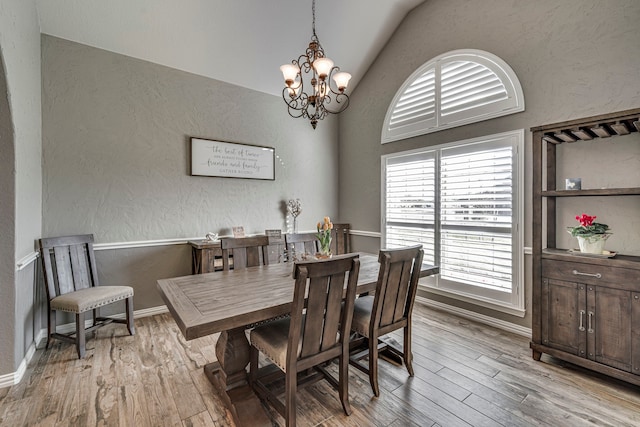 dining area featuring light hardwood / wood-style flooring, an inviting chandelier, and lofted ceiling