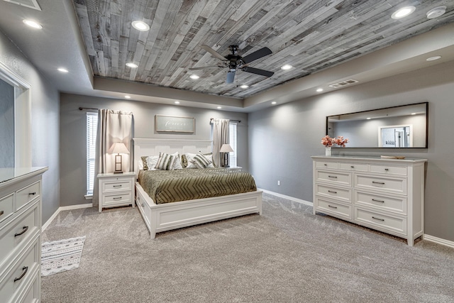 unfurnished bedroom with ceiling fan, light colored carpet, and a tray ceiling