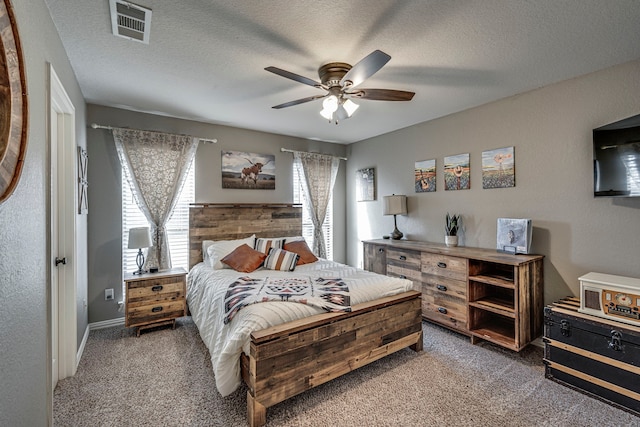 carpeted bedroom featuring ceiling fan and a textured ceiling