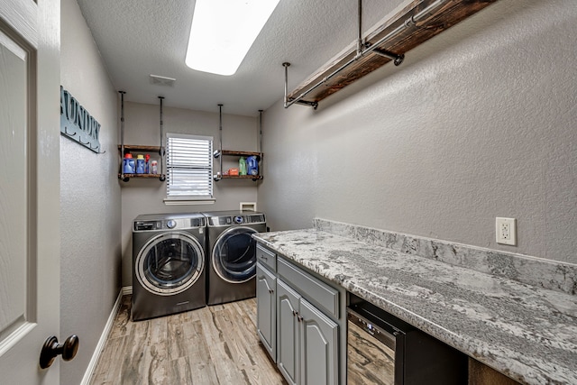 laundry room featuring washer and dryer, cabinets, a textured ceiling, and light hardwood / wood-style flooring