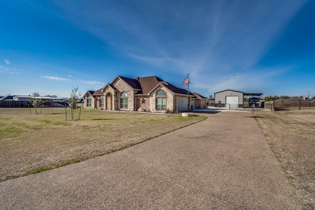 single story home featuring a garage, a front lawn, and an outdoor structure