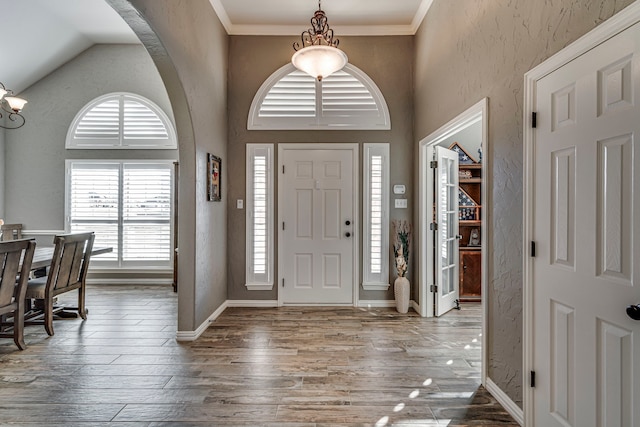 foyer entrance featuring hardwood / wood-style floors, a high ceiling, and ornamental molding