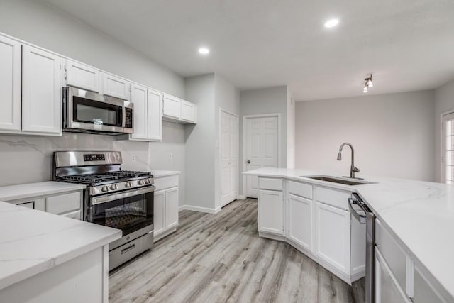 kitchen featuring white cabinetry, appliances with stainless steel finishes, light stone countertops, and sink