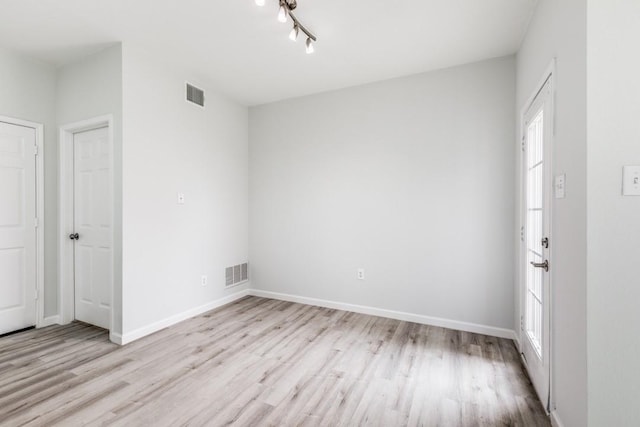 unfurnished room with track lighting and light hardwood / wood-style flooring