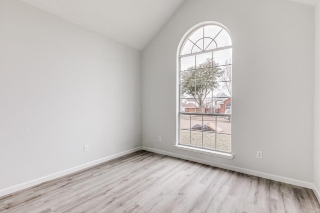 empty room with a healthy amount of sunlight, lofted ceiling, and light hardwood / wood-style flooring