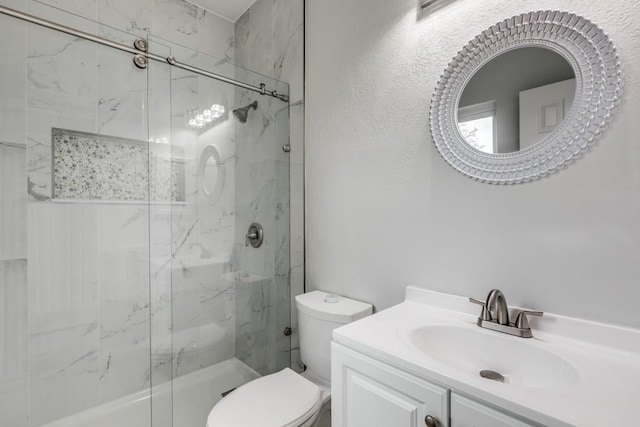 bathroom with toilet, vanity, and a shower with shower door