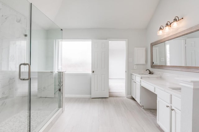 bathroom featuring a shower with door, vanity, and lofted ceiling