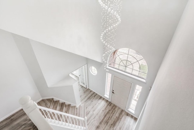 foyer with a notable chandelier, a towering ceiling, and light wood-type flooring