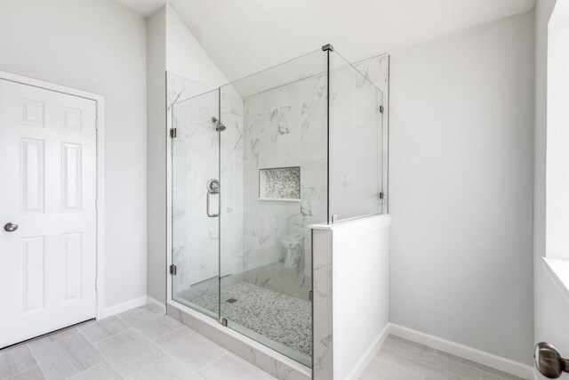 bathroom featuring a shower with door, vanity, and vaulted ceiling