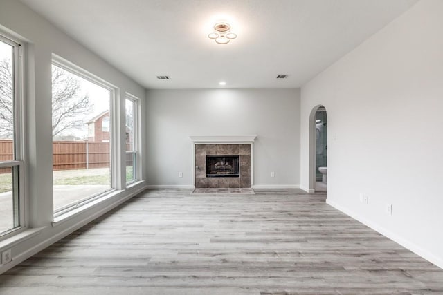 unfurnished living room featuring a tiled fireplace and light hardwood / wood-style floors