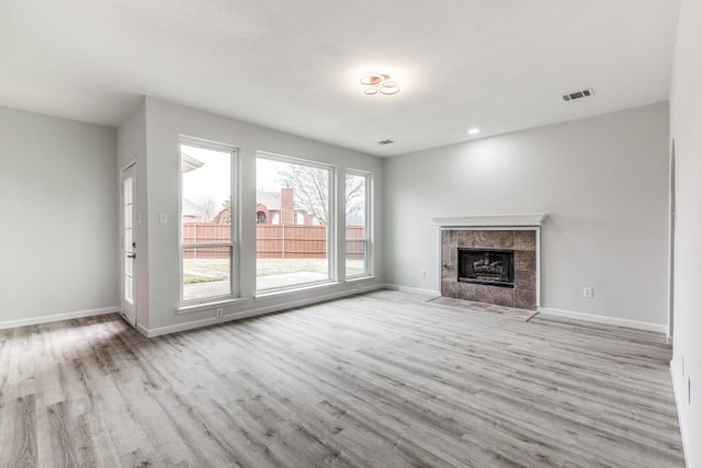 unfurnished living room featuring a tile fireplace and light wood-type flooring