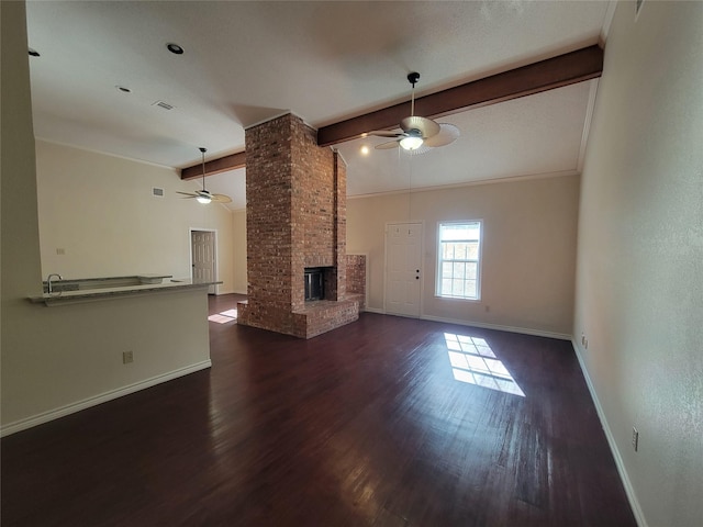 unfurnished living room with dark wood-type flooring, ceiling fan, lofted ceiling with beams, and a brick fireplace