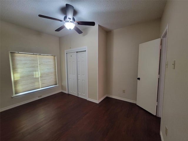 unfurnished bedroom featuring ceiling fan, a textured ceiling, dark hardwood / wood-style floors, and a closet