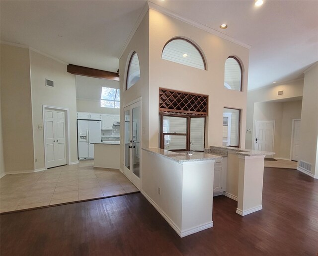 kitchen with light hardwood / wood-style flooring, white cabinetry, a high ceiling, and white refrigerator with ice dispenser