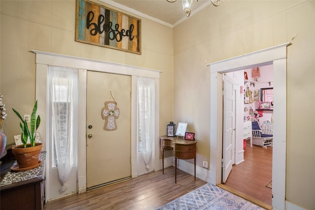 entryway with ornamental molding and hardwood / wood-style floors