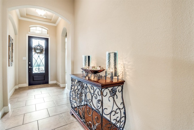 tiled foyer entrance featuring a raised ceiling and ornamental molding