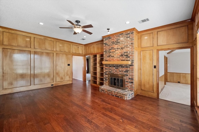 unfurnished living room featuring ceiling fan, wood walls, dark hardwood / wood-style floors, and a fireplace