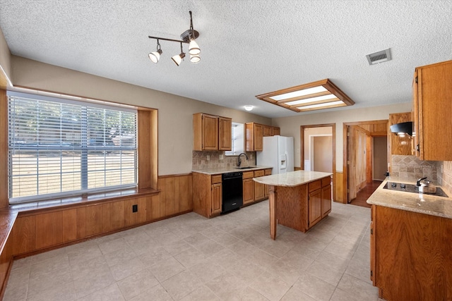 kitchen featuring sink, exhaust hood, a center island, wood walls, and black appliances