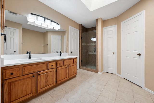 bathroom with tile patterned floors, walk in shower, a skylight, and vanity