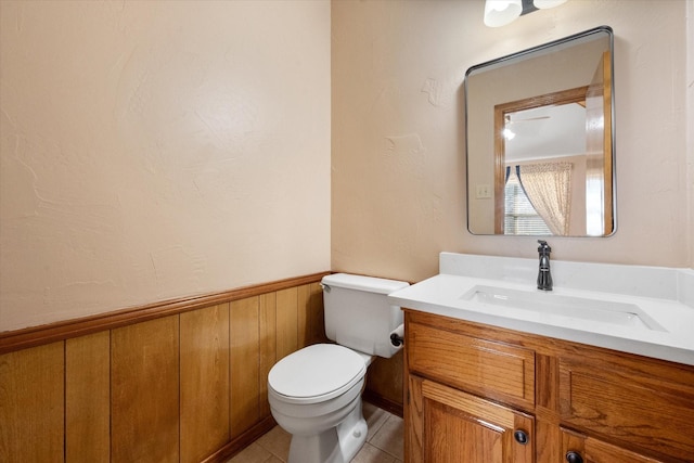 bathroom featuring vanity, toilet, wood walls, and tile patterned flooring