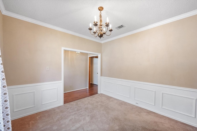 spare room with a chandelier, crown molding, and a textured ceiling