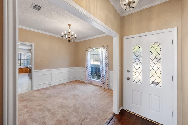 carpeted entryway with ornamental molding, a healthy amount of sunlight, and an inviting chandelier