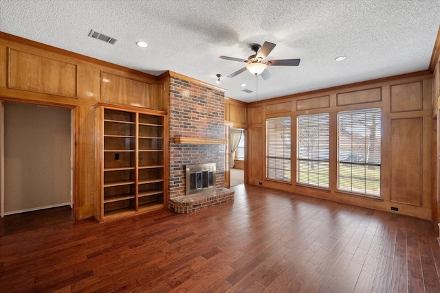 unfurnished living room with ceiling fan, a textured ceiling, a brick fireplace, and dark hardwood / wood-style flooring