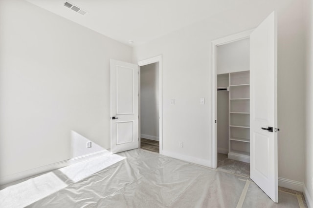 unfurnished bedroom featuring light carpet, a closet, and a walk in closet