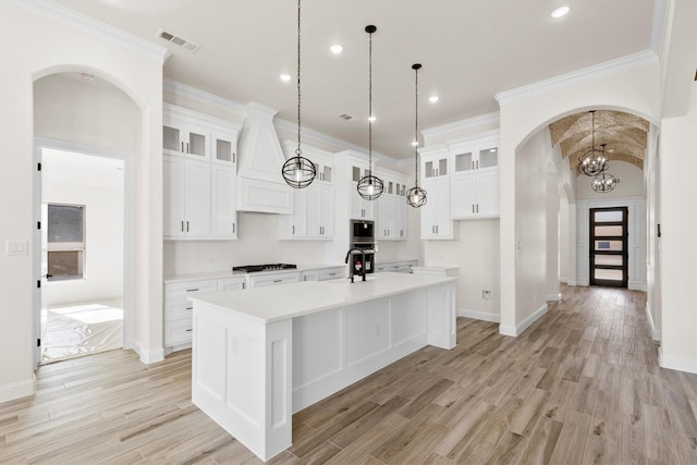 kitchen with white cabinetry, gas stovetop, hanging light fixtures, and an island with sink