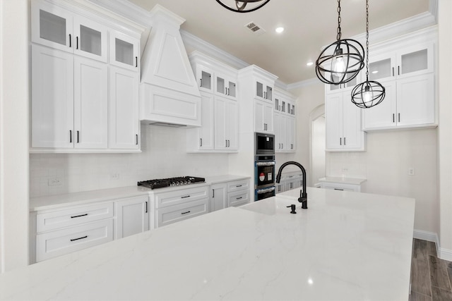 kitchen with white cabinets, stainless steel appliances, custom range hood, and light stone counters