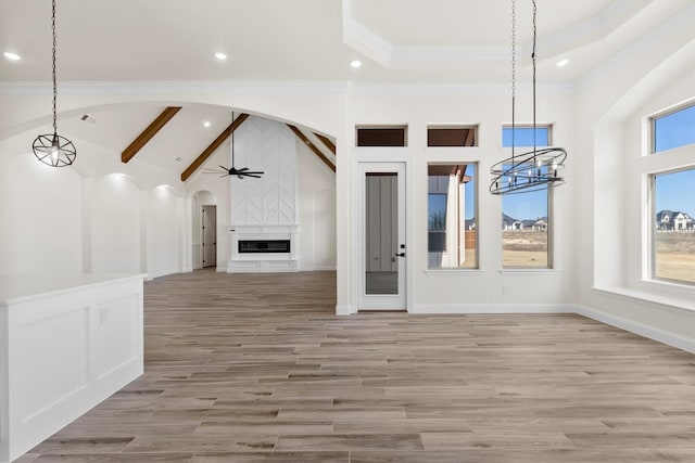 unfurnished living room with crown molding, light hardwood / wood-style flooring, a fireplace, ceiling fan with notable chandelier, and vaulted ceiling with beams