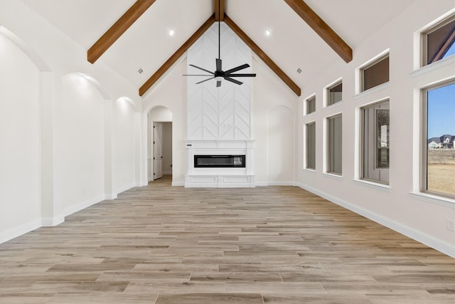 unfurnished living room with high vaulted ceiling, light hardwood / wood-style flooring, and beamed ceiling