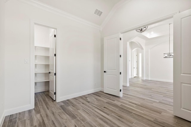 unfurnished bedroom featuring crown molding, light hardwood / wood-style floors, a closet, and a walk in closet