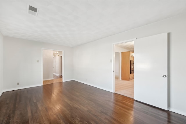 unfurnished room featuring dark hardwood / wood-style flooring and a notable chandelier