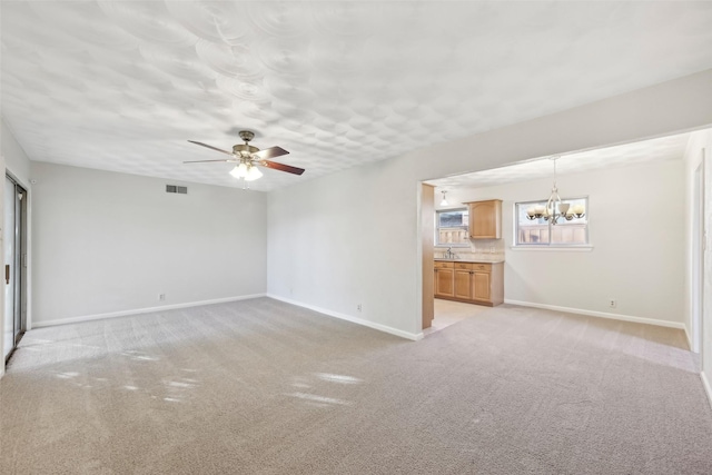 unfurnished living room with ceiling fan with notable chandelier and light colored carpet