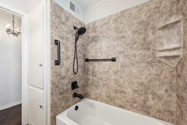 bathroom with an inviting chandelier and tiled shower / bath combo