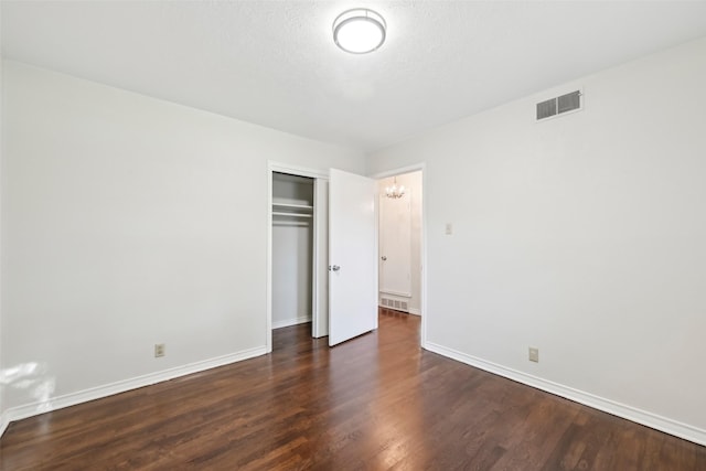 unfurnished bedroom featuring a closet and dark hardwood / wood-style flooring