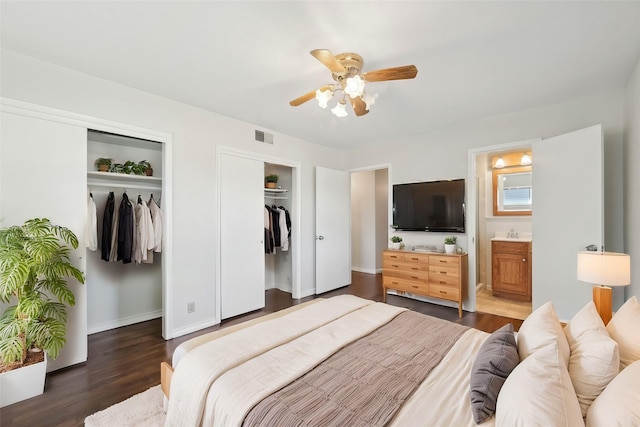 bedroom featuring multiple closets, sink, dark wood-type flooring, ceiling fan, and connected bathroom