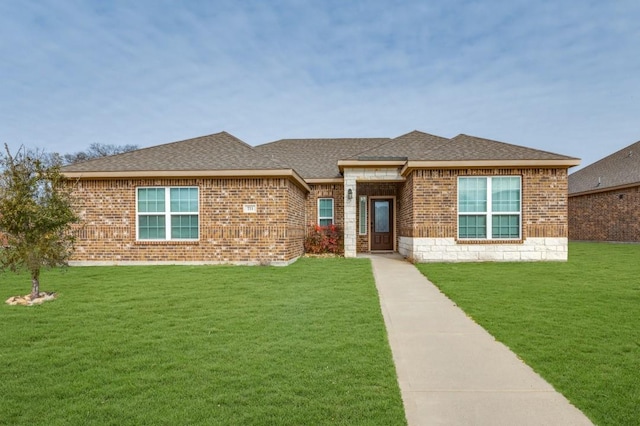 view of front facade featuring a shingled roof, a front lawn, and brick siding