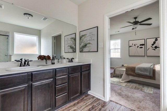 ensuite bathroom featuring double vanity, visible vents, ensuite bath, wood finished floors, and a sink